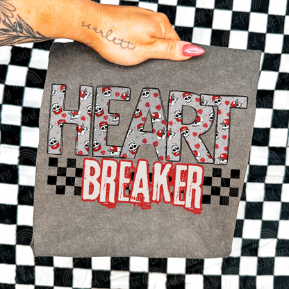 Grey shirt with the word heart breaker. Inside the word heart is a skull wearing a red truckers hat and red conversation hearts. Underneath the word breaker is a black checkered background. Perfect for a valentines t-shirt. 